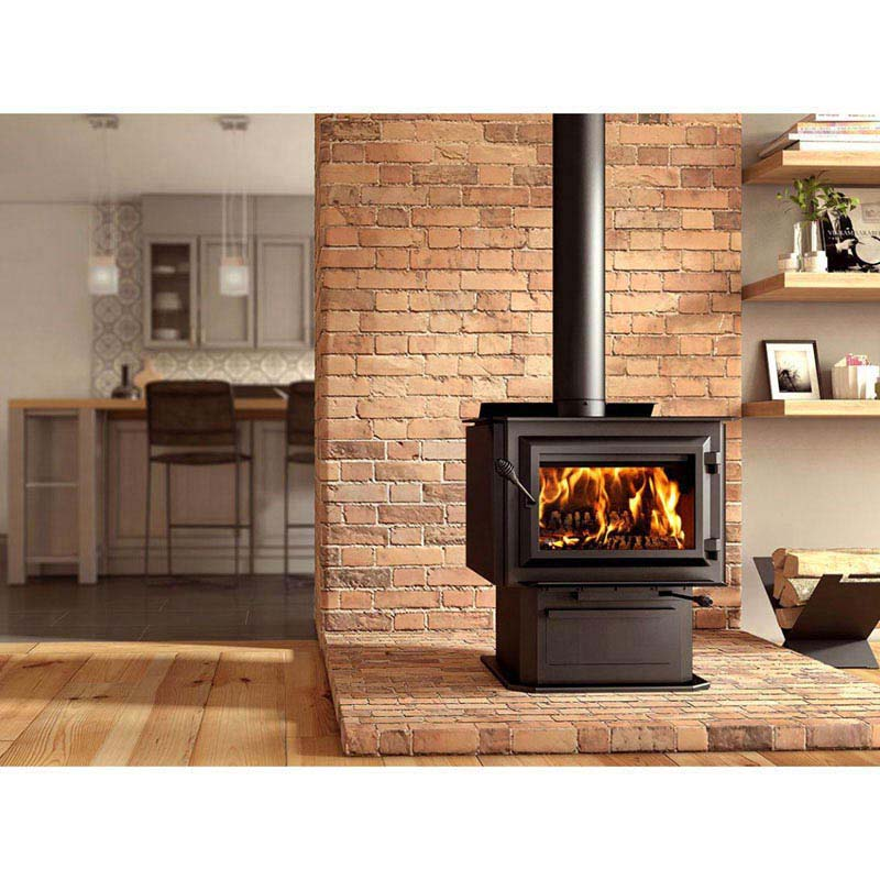 Cozy living space with a lit wood-burning stove against a brick wall, warm wooden flooring, and a modern kitchen in the background.